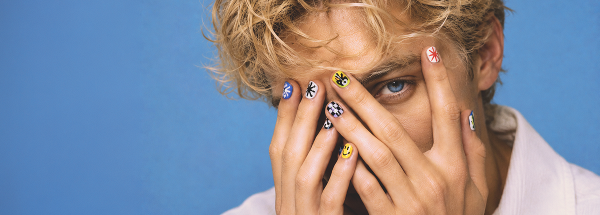 Person with colorful nail polish covering face against a blue background