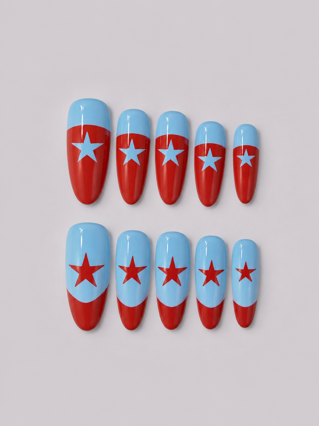 Ten artificial press-on nails arranged in two rows on a light gray background. Each nail is glossy and features a red and light blue design with a star motif, resembling the Chicago city flag.