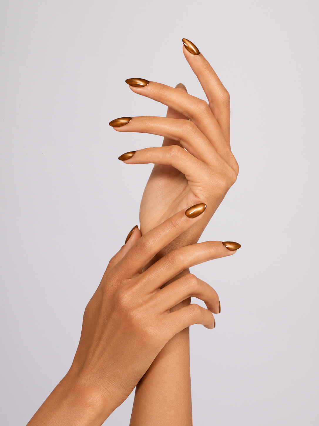 Two hands with metallic bronze nail polish, posed against a solid light gray background.
