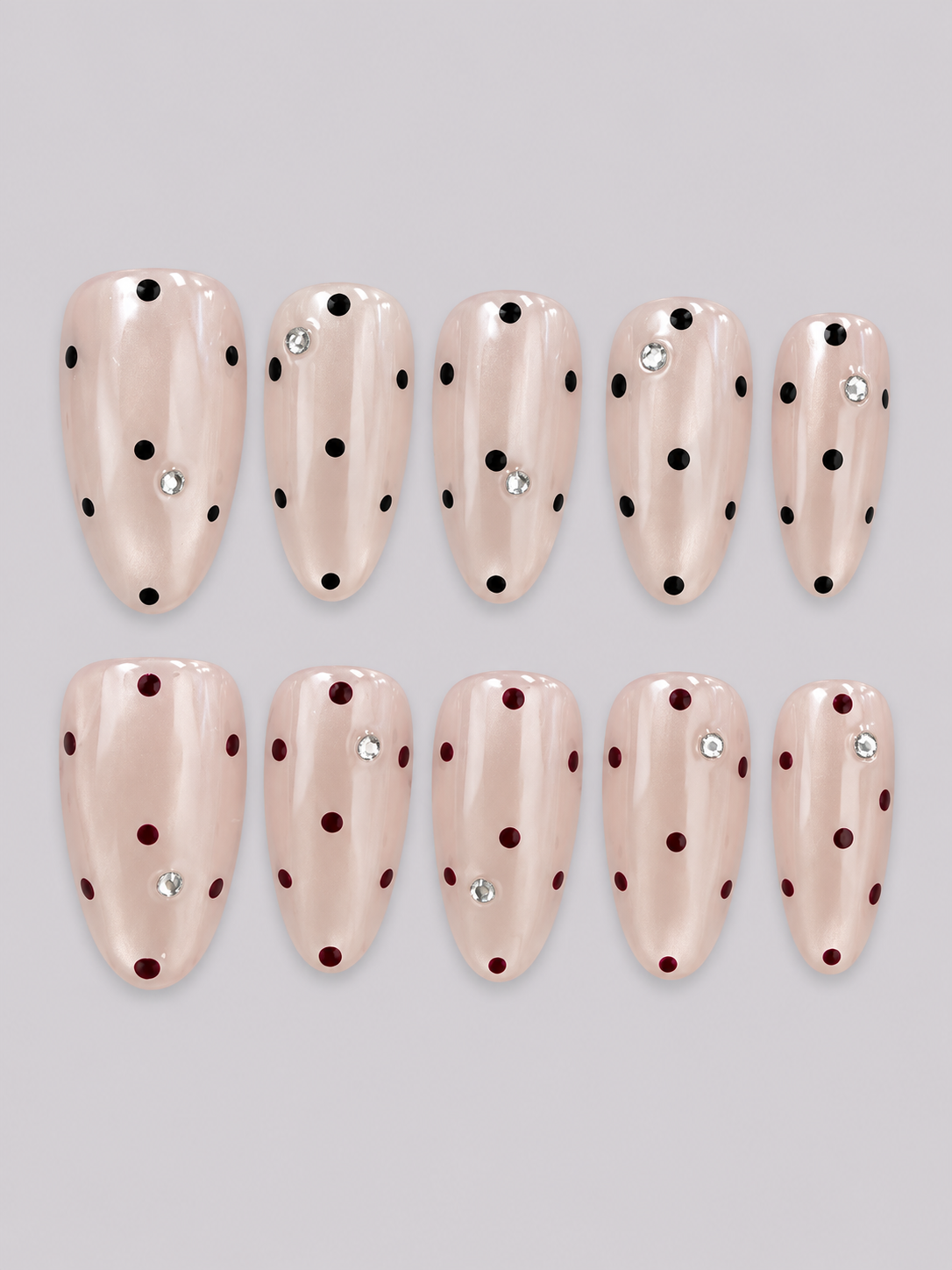 Hepburn Dots press-on nail set with a pearly nude base, black and burgundy polka dots, and small sparkling accents.