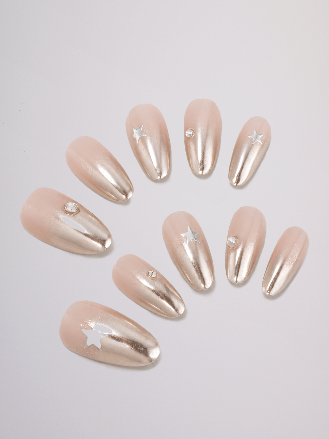 Two hands with long, almond-shaped nails painted in a glossy nude-pink and silver manicure, posed against a solid light gray background.