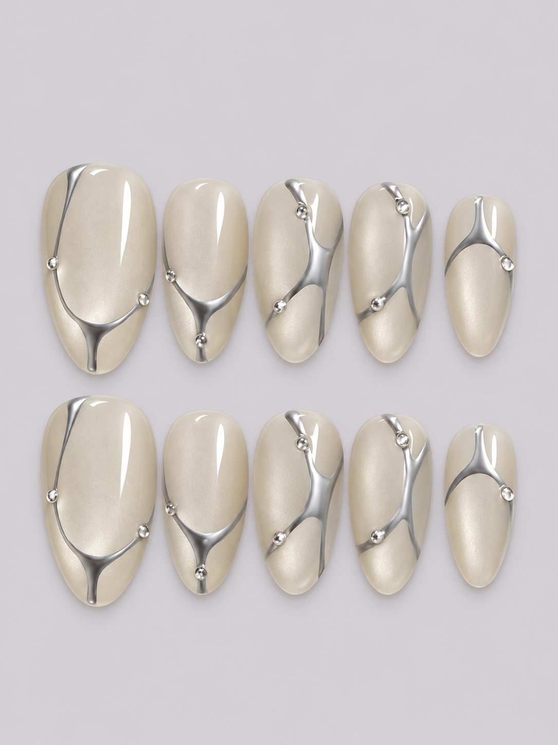 Hands wearing Silver Current press-on nails with flowing silver chrome lines and bead details over a translucent milky base.