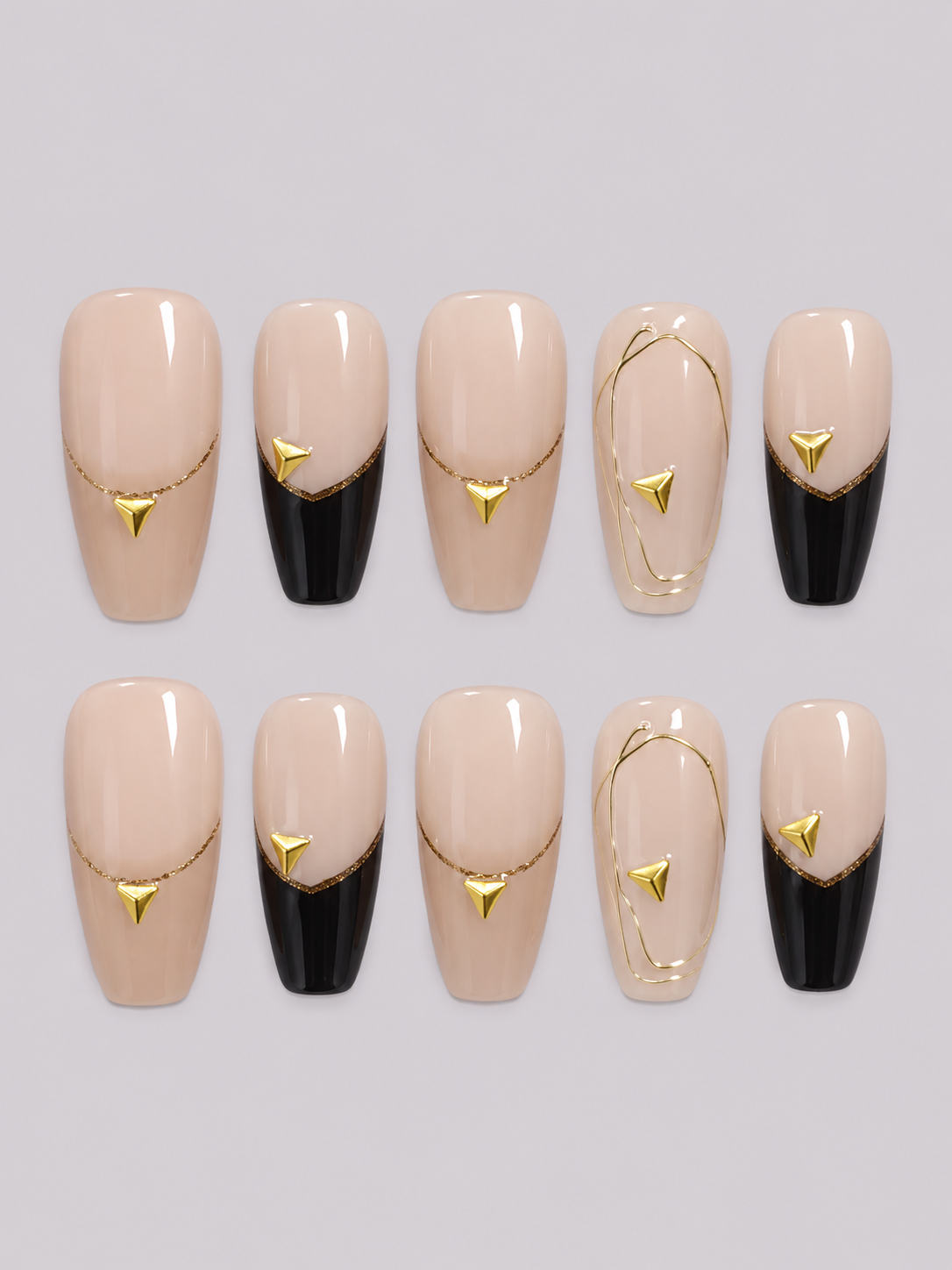 Amber Affair press-on nail set with nude bases, black tips, fine gold lines and triangular gold accents.