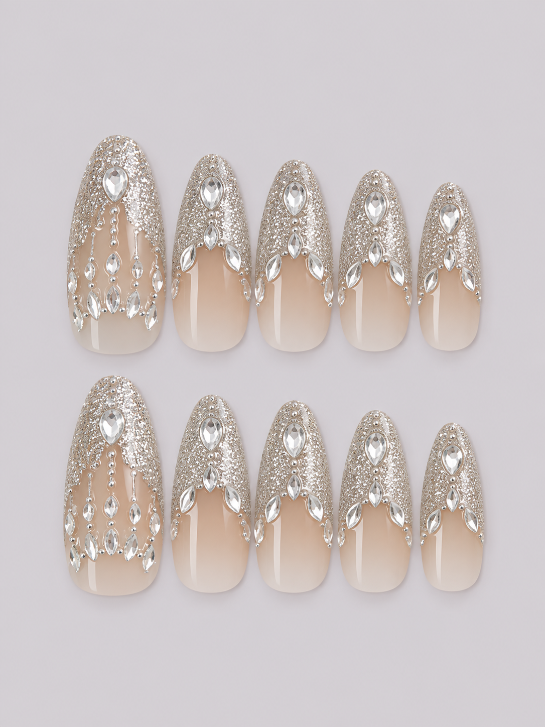 Crowned press-on nail set with silver glitter and cascading gem decorations over a nude-to-milky base.