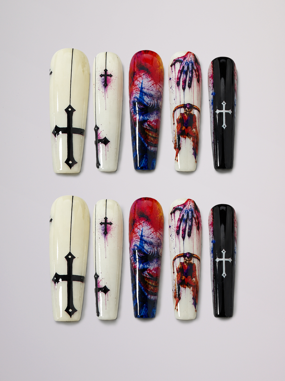 Six coffin-shaped press-on nails arranged in two rows of three on a light gray background. The set includes designs with black crosses on cream and black bases, and two nails featuring a red, blue, and purple marbled splatter pattern with a zombie hand graphic.