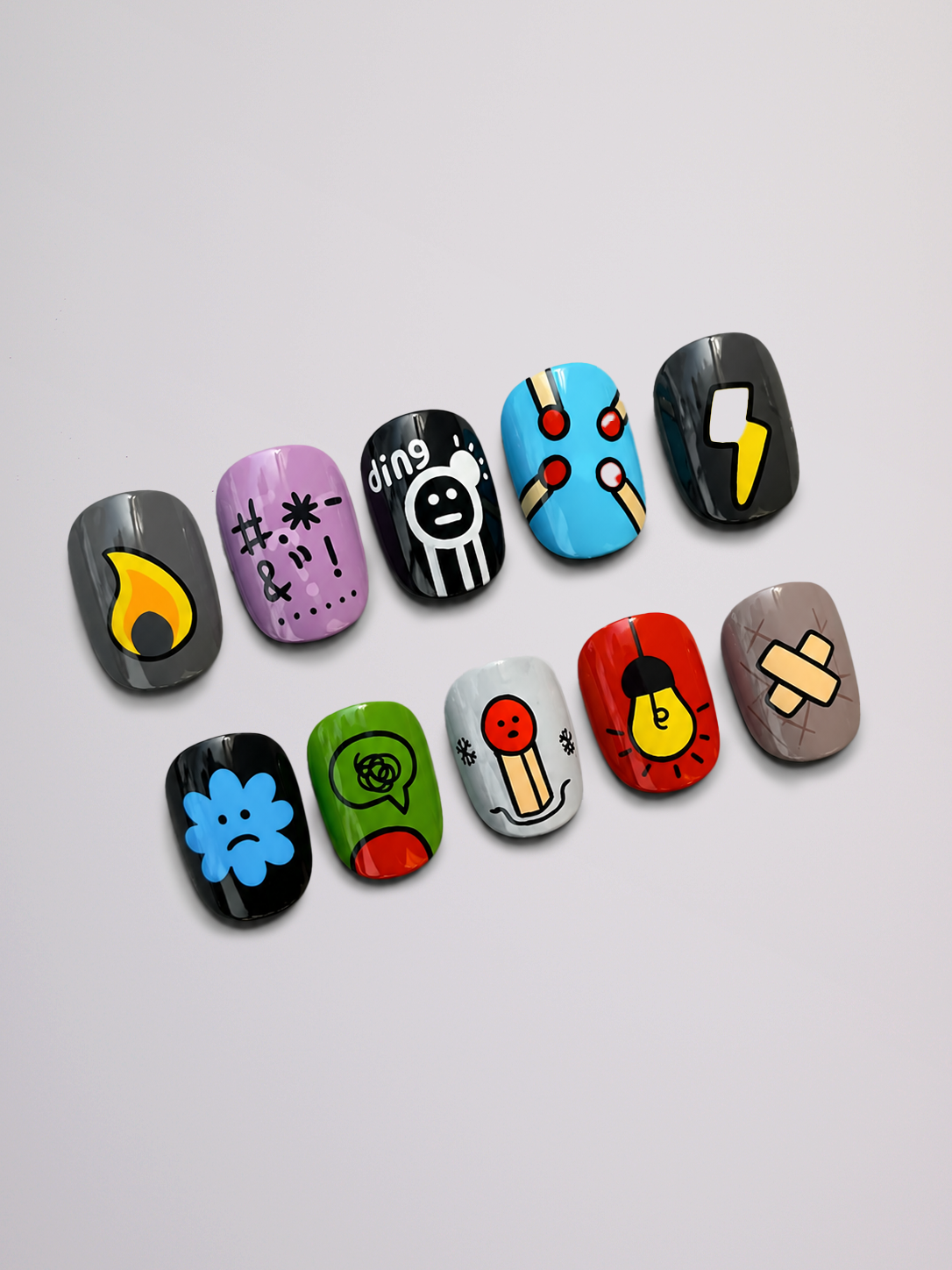 A set of ten false press-on nails with various colorful hand-painted doodle designs, arranged in two rows on a light gray background.
