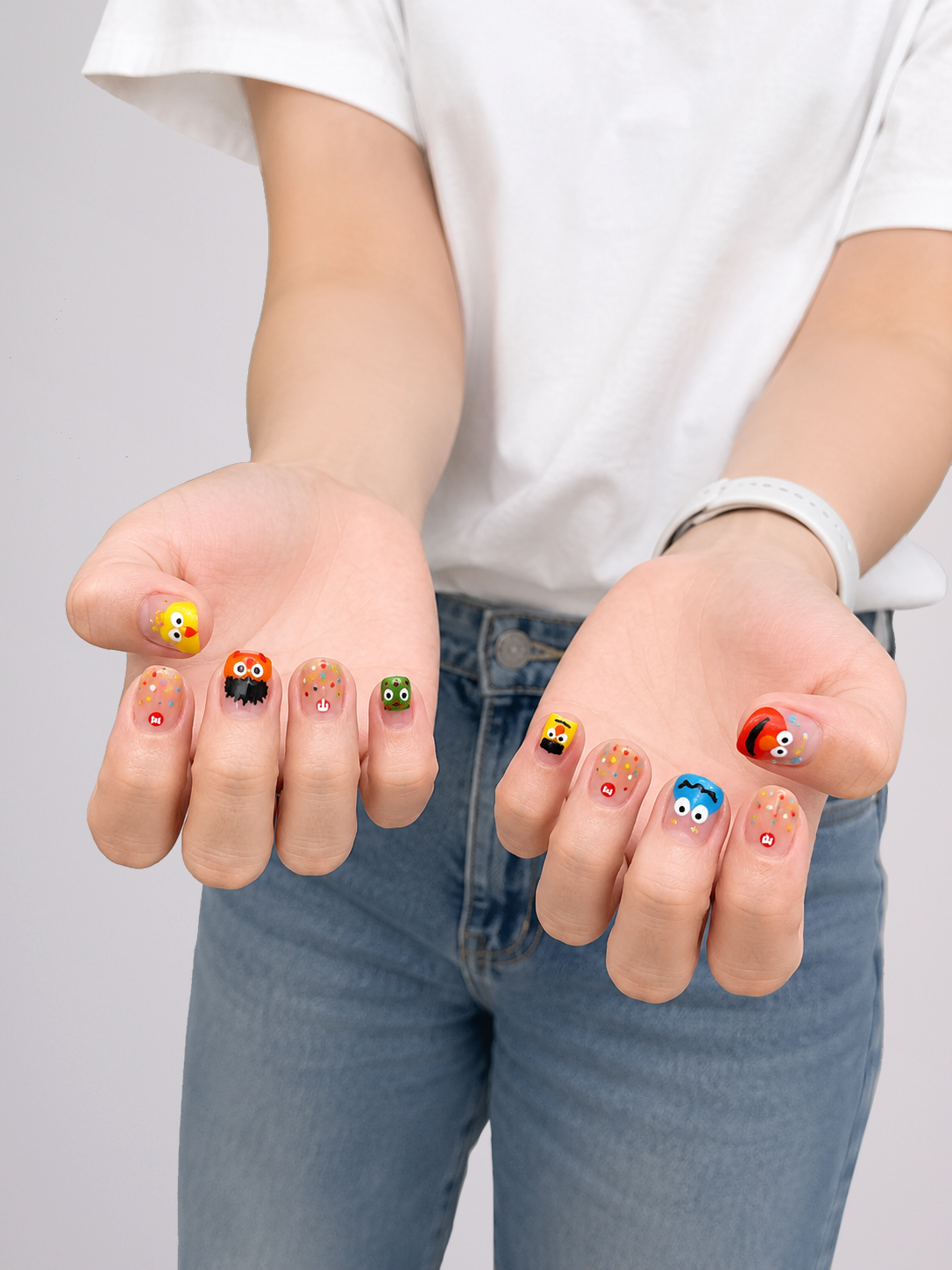 A pair of hands with colorful cartoon-themed nail art, shown against a plain light gray background.