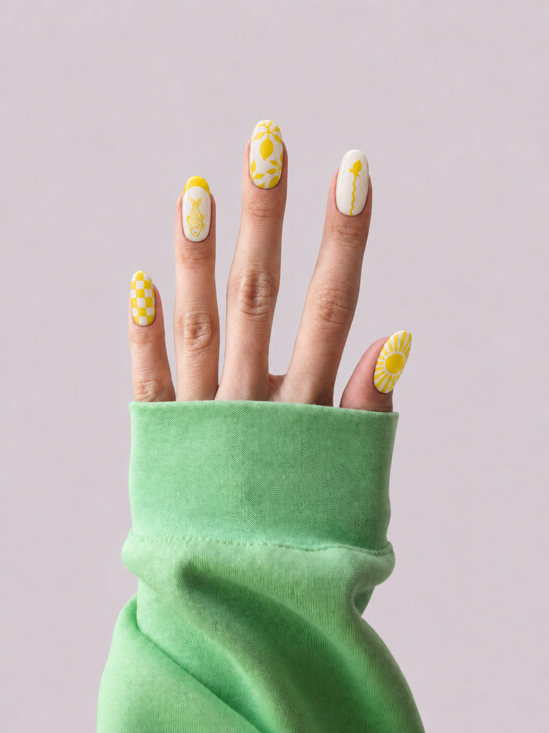 A close-up of a hand with yellow and white nail art designs, emerging from a green sleeve against a solid light gray background.
