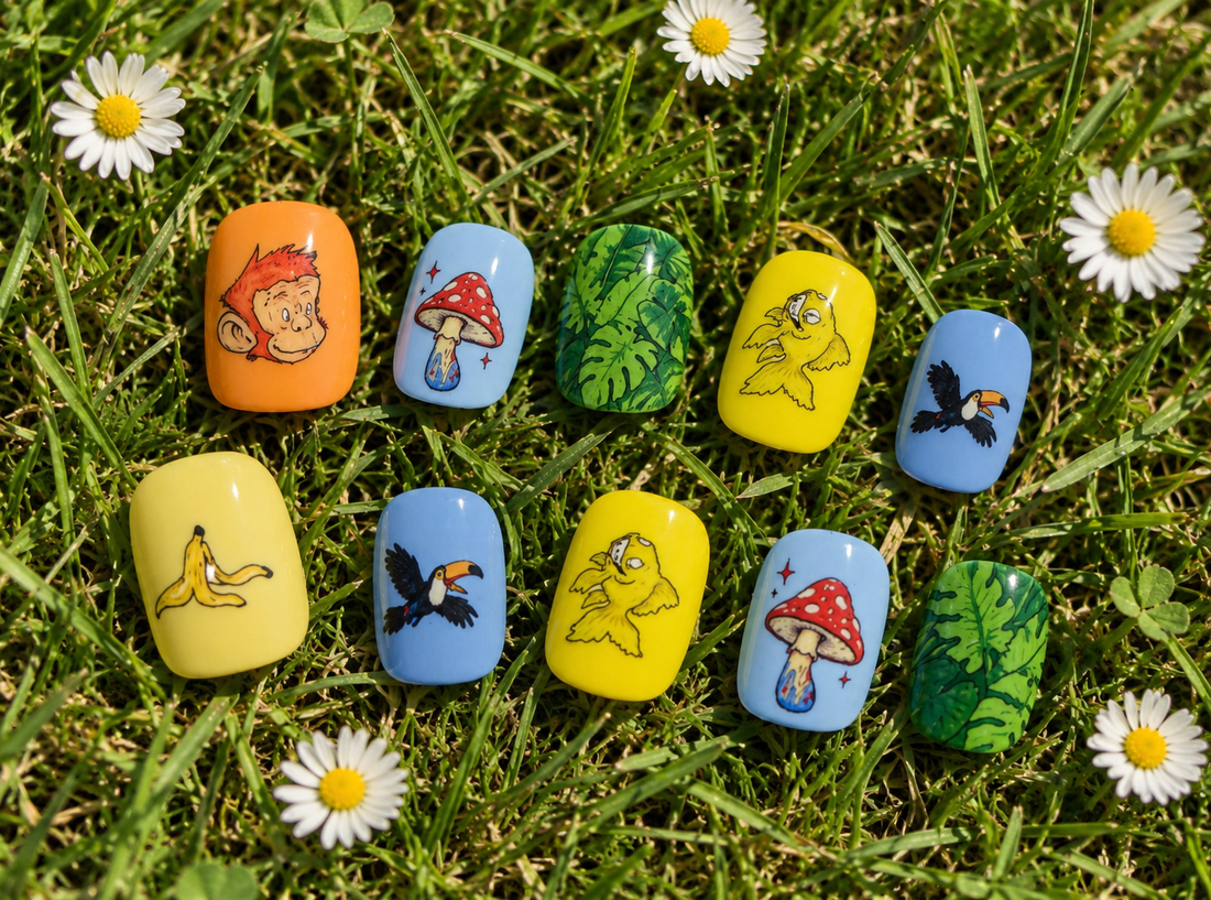 Hand wearing CLAWT x Dario Merlo illustrated press-on nails and chunky rings, surrounded by ferns and mushrooms.