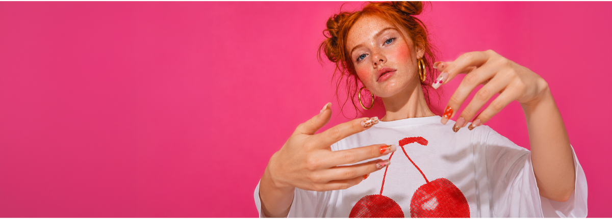 Woman wearing a white t-shirt with red cherries on a pink background